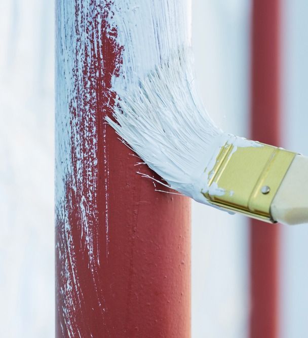 mano de pintor aplica blanco a tubo rojo